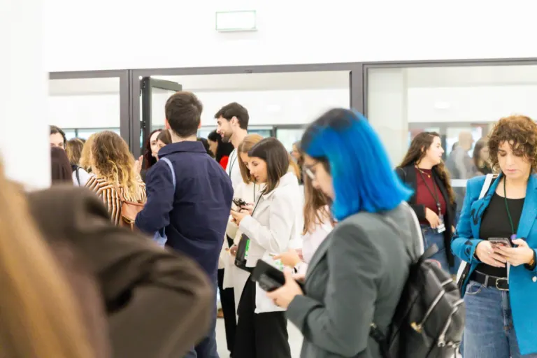 Grupo de pessoas em uma fila de conferência ou evento, interagindo e usando celulares em um ambiente interno