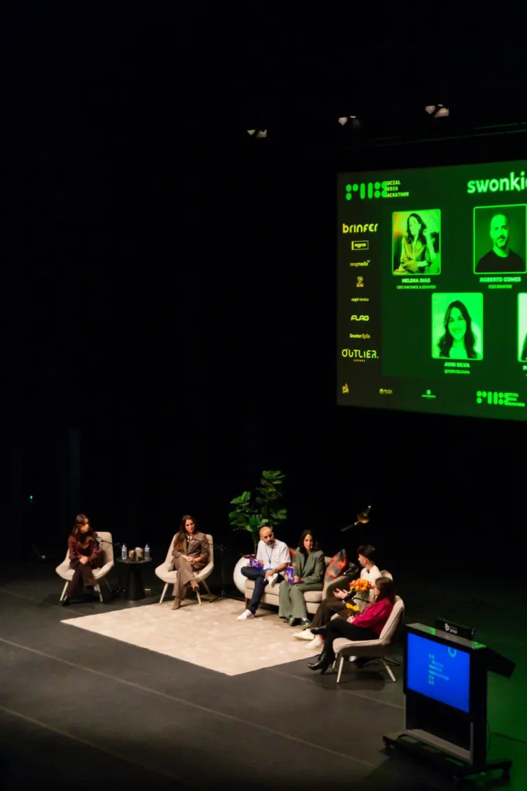 Painel de uma conferência ou painel de discussão, com várias pessoas sentadas em cadeiras, algumas segurando livros ou...