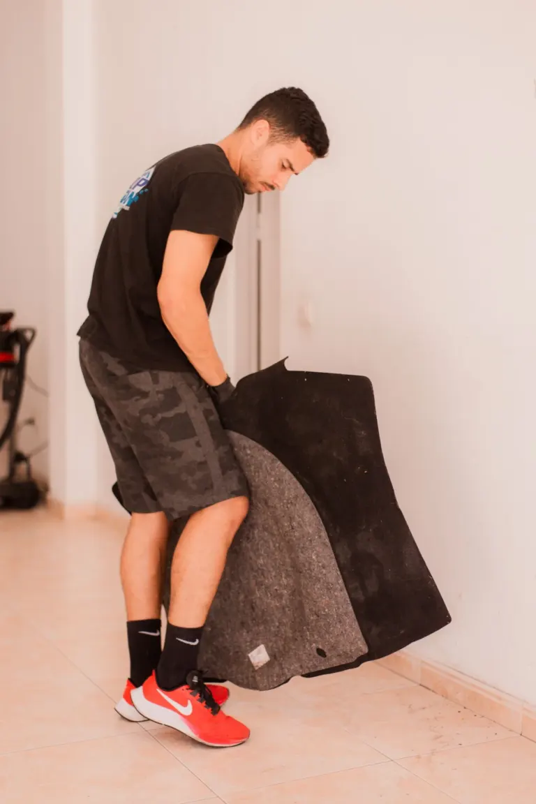 Homem segurando uma peça de carpete ou tapete, em um ambiente interno